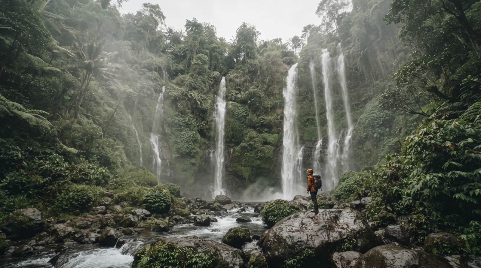 Two tall ribbons of white water dropping side by side down a green jungle cliff into a misty valley, sekumpul waterfall, Buleleng regency, north Bali